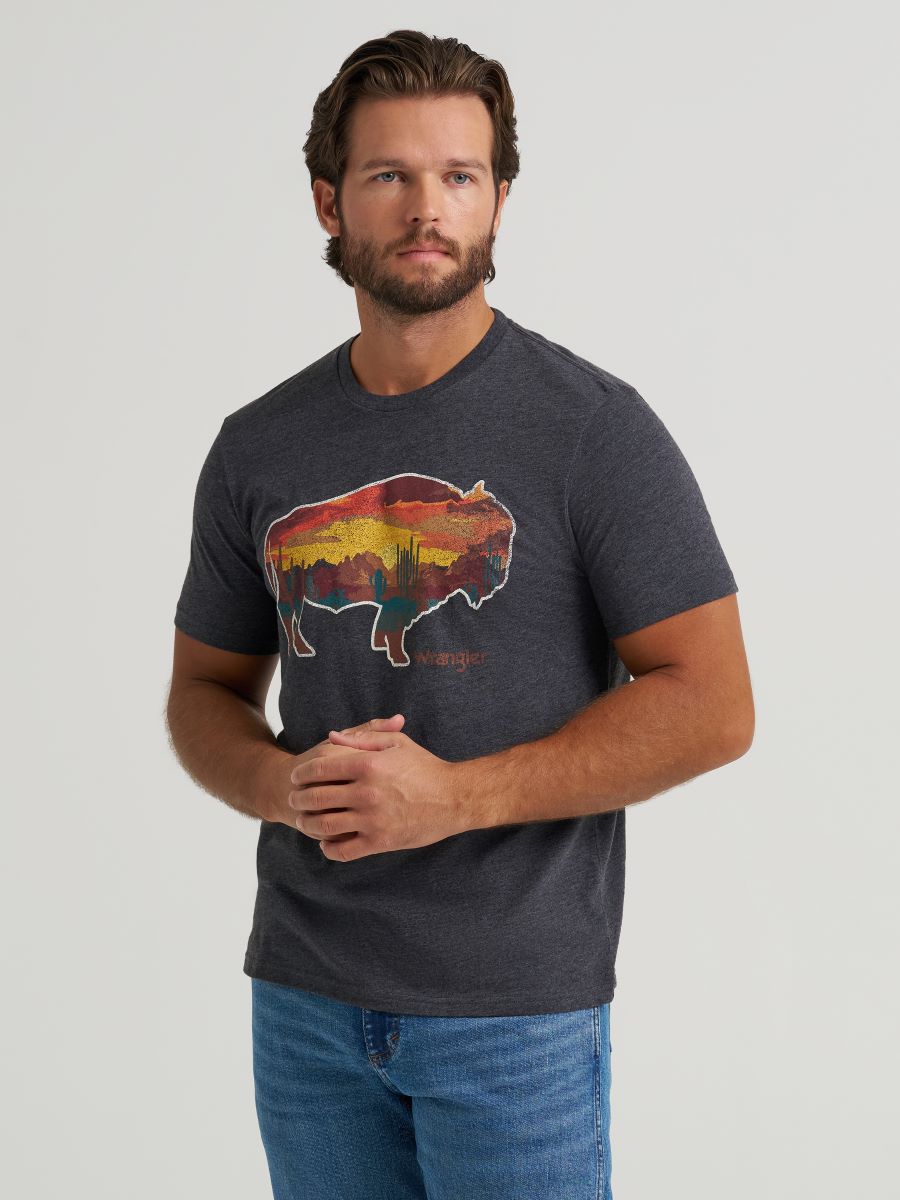 Man wearing a dark gray t-shirt with a colorful graphic design on a light gray background