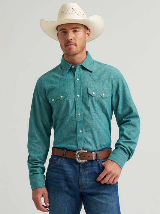 Man wearing a green long-sleeve shirt, blue jeans, and a white cowboy hat on a gray background