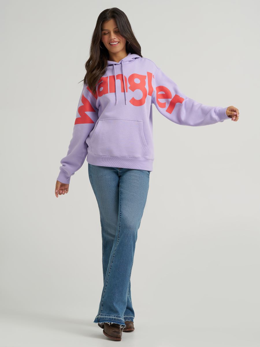 Person wearing a light purple hoodie with red text and blue jeans on a gray background