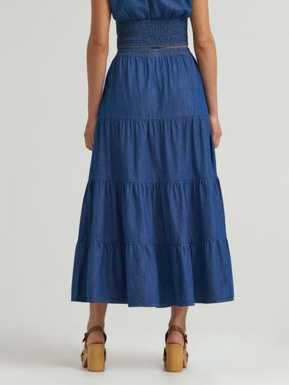 Blue tiered denim dress worn by a person on a white background