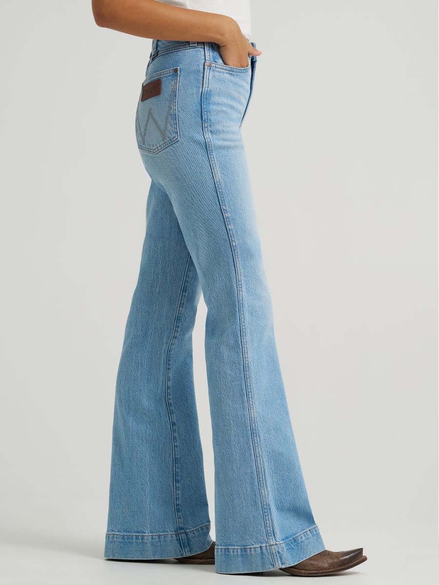 Light blue flared jeans worn by a person on a light gray background