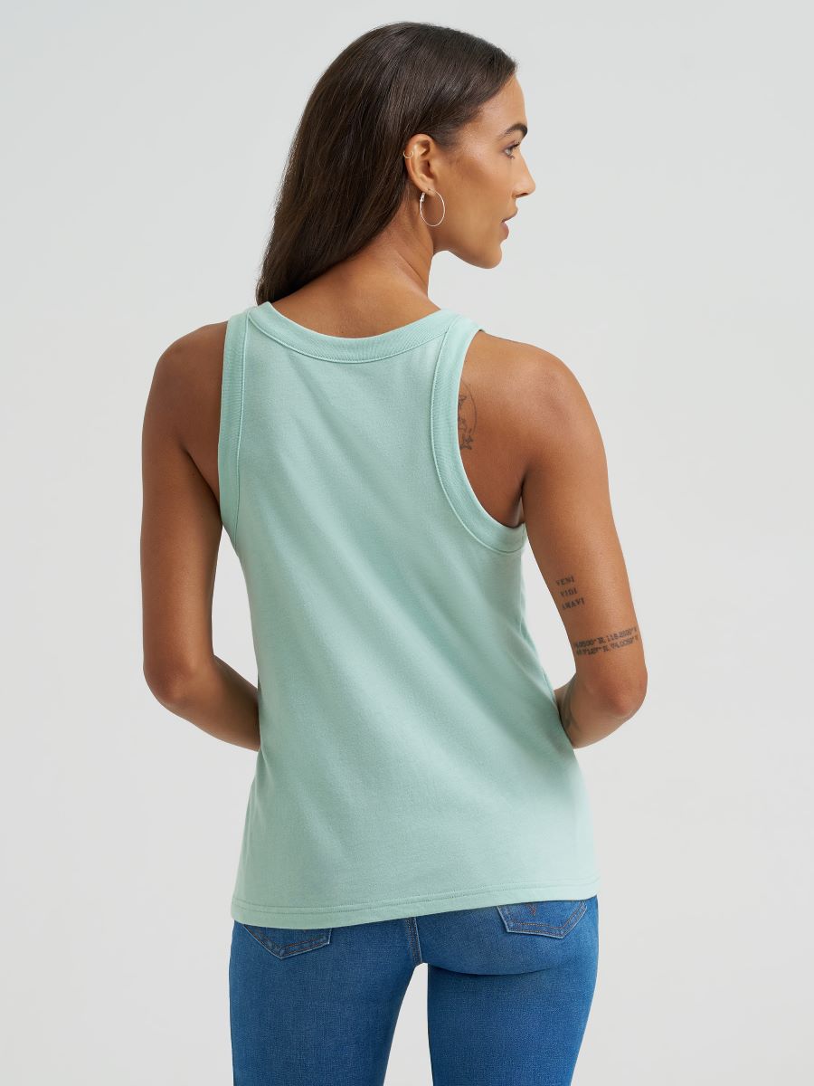 Woman wearing a light green Wrangler tank top and blue jeans on a plain background
