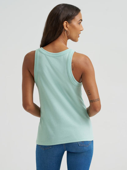 Woman wearing a light green Wrangler tank top and blue jeans on a plain background