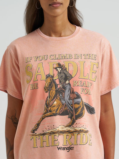 Person wearing a pink Wrangler t-shirt with a graphic of a person on a horse and text.