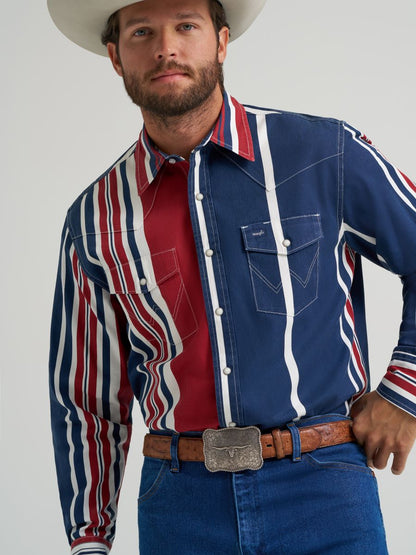 Man wearing a colorful striped Wrangler shirt, blue jeans, and a cowboy hat on a gray background
