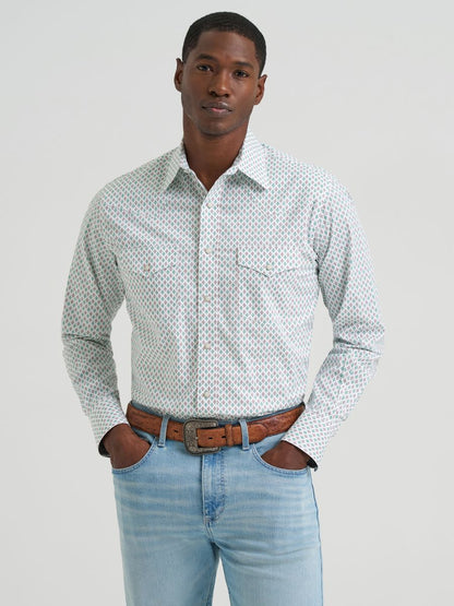 Man wearing a green and brownpatterned Wrangler shirt and light blue jeans against a plain background