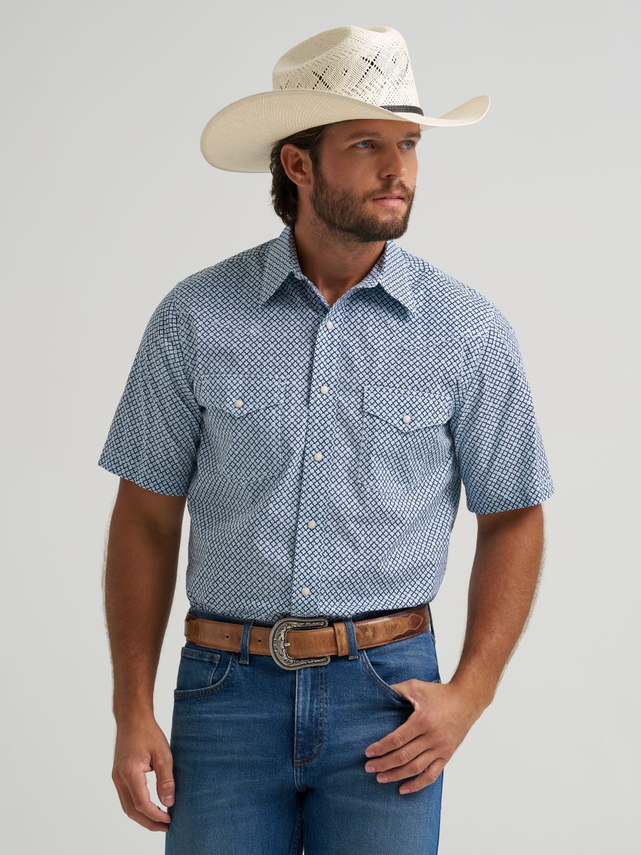 man wearing a printed Wrangler shirt, blue jeans and a cowboy hat on a white background