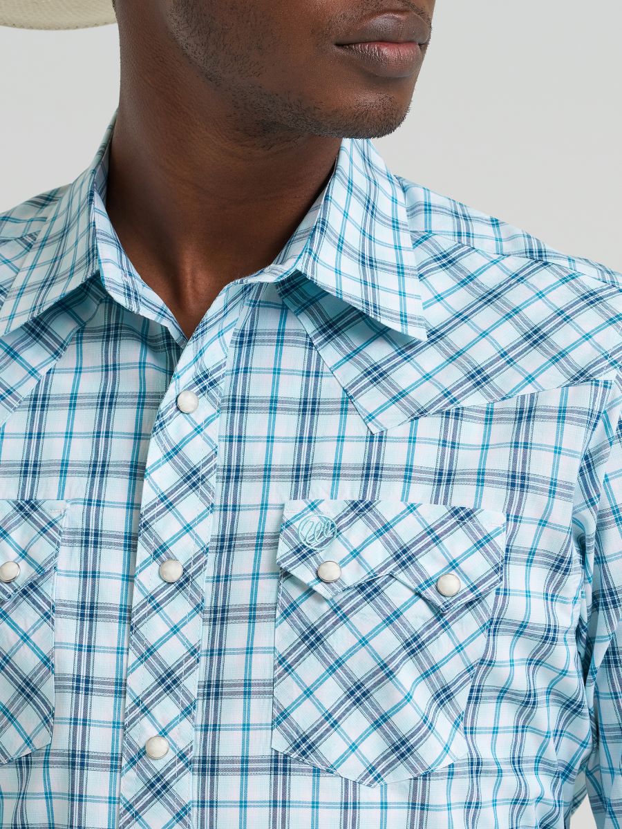 Close-up of a person wearing a blue and white plaid Wrangler shirt with a neutral background