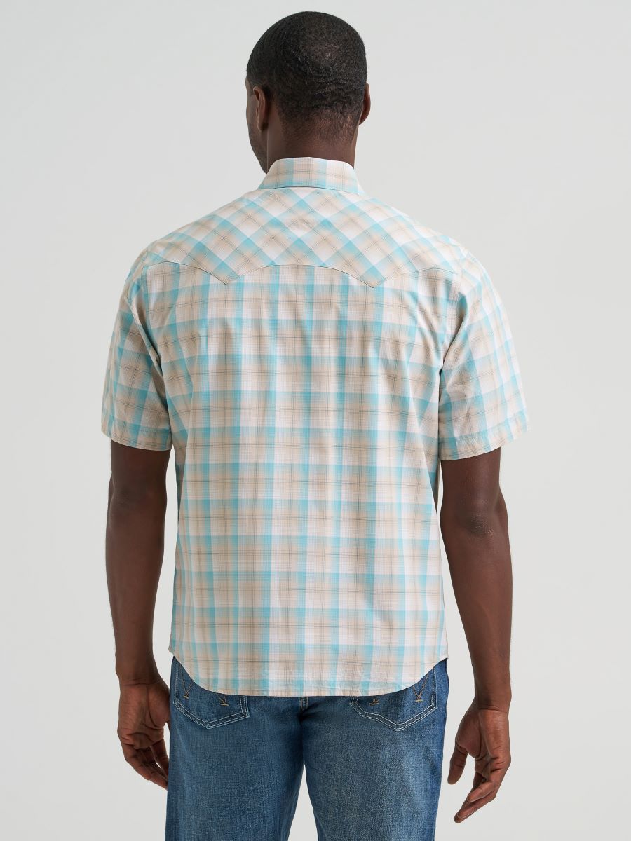 Man wearing a plaid Wrangler shirt and jeans on a plain background