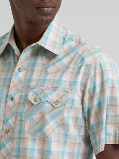 Close-up of a man wearing a short-sleeve Wrangler plaid shirt in light blue and beige, showing the collar, chest pocket, and snap-button placket.