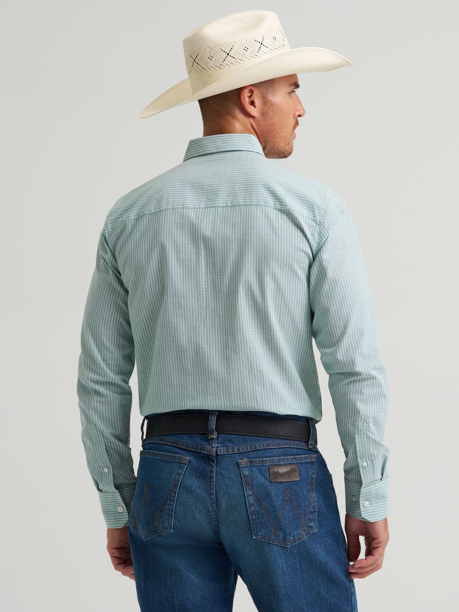 Man wearing a light green Wrangler checkered shirt, white cowboy hat, and blue jeans on a gray background