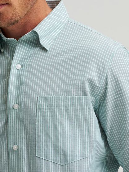 Close-up of a person wearing a light green striped Wrangler shirt with a neutral background