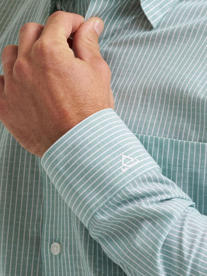 Close-up of a hand adjusting the sleeve of a green striped Wrangler shirt with a brand logo.