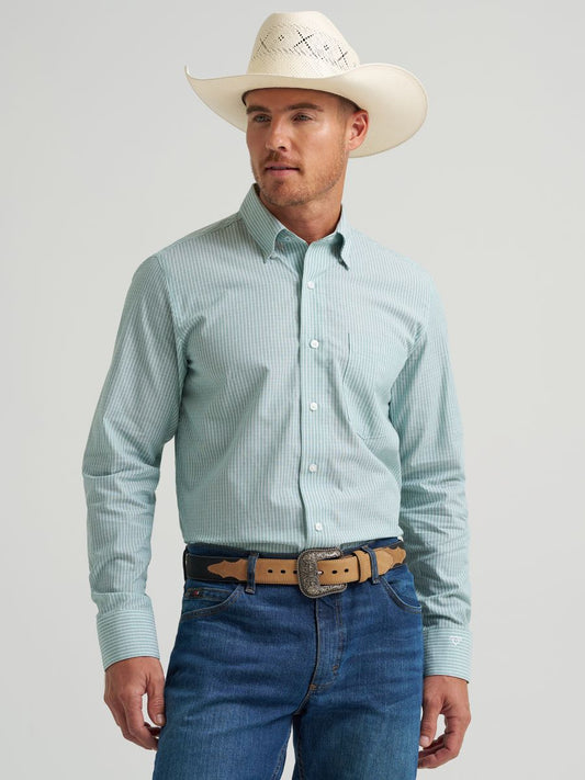 Man wearing a light green Wrangler checkered shirt, white cowboy hat, and blue jeans on a gray background