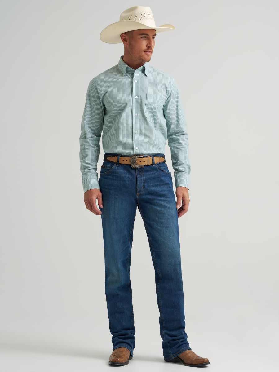 Man wearing a light green Wrangler checkered shirt, white cowboy hat, and blue jeans on a gray background