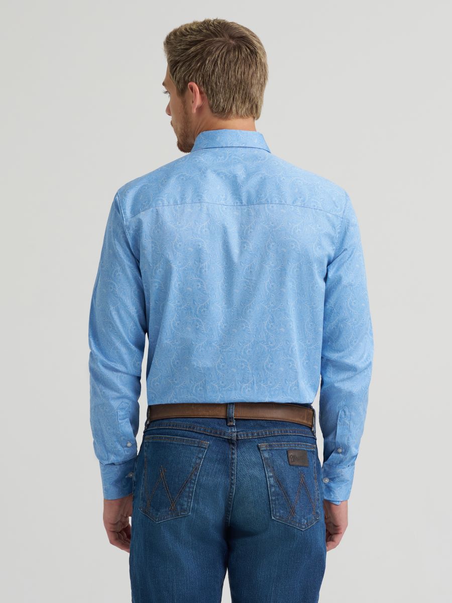 Man wearing a light blue button-up Wrangler shirt and jeans on a gray background
