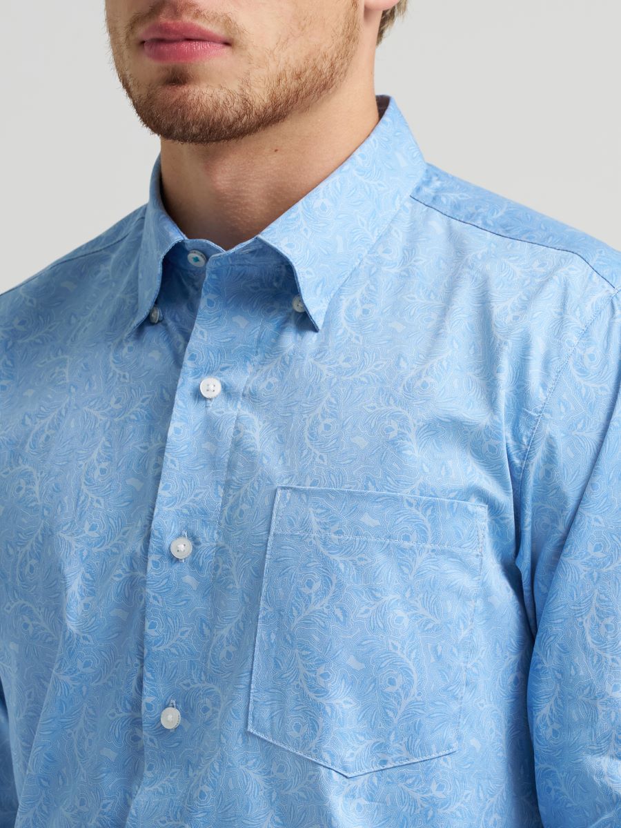 Man wearing a light blue button-up Wrangler shirt  on a gray background