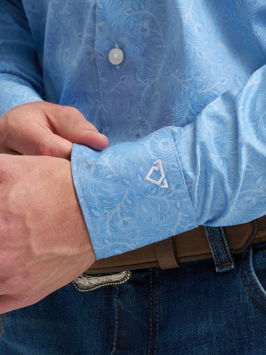 Close-up of a person wearing a blue patterned Wrangler shirt with a visible brand logo on the cuff.