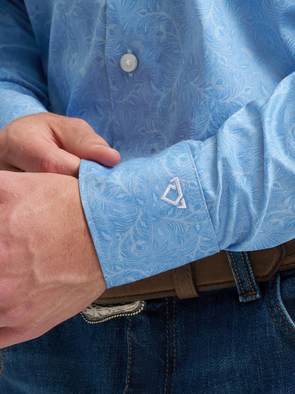 Close-up of a person wearing a blue patterned Wrangler shirt with a visible brand logo on the cuff.