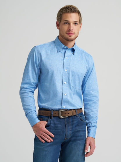 Man wearing a light blue button-up Wrangler shirt and jeans on a gray background