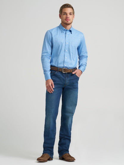 Man wearing a light blue button-up Wrangler shirt and jeans on a gray background