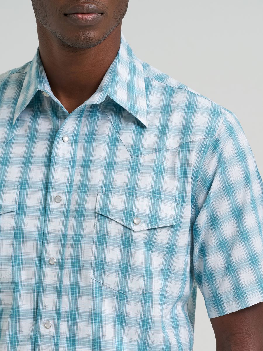 Man wearing a blue and white checkered Wrangler shirt against a gray background