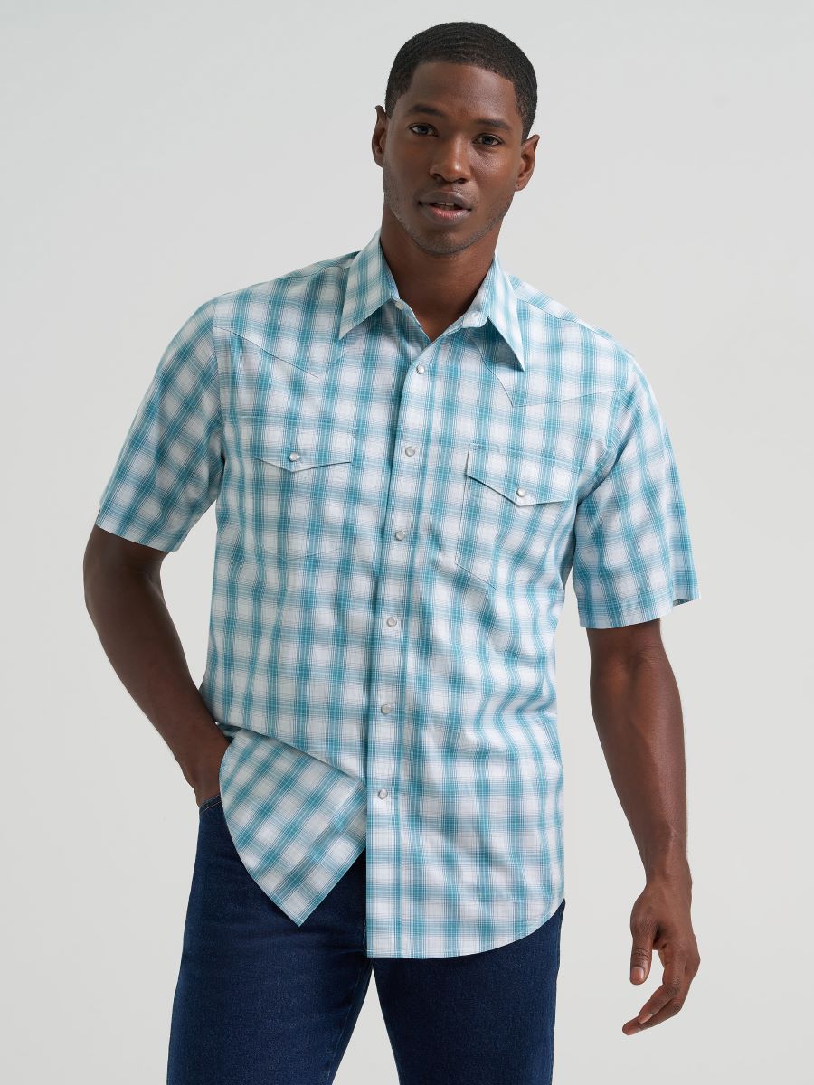 Man wearing a blue and white checkered  Wrangler shirt against a plain background