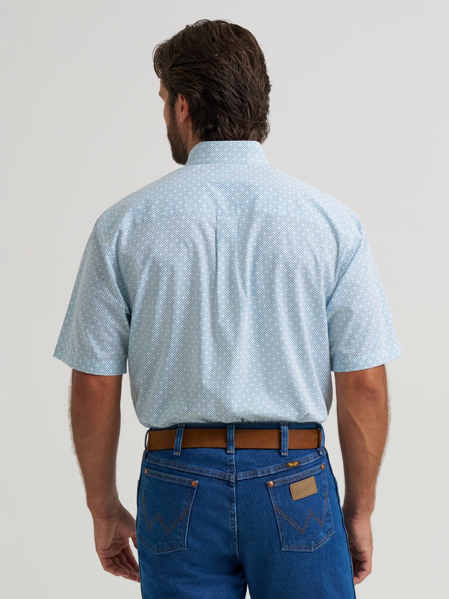 Man wearing a light blue patterned Wrangler shirt and blue jeans on a plain background