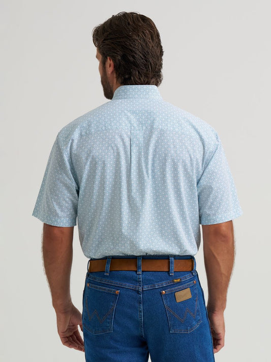 Man wearing a light blue patterned Wrangler shirt and blue jeans on a plain background