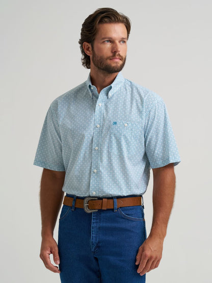 Man wearing a light blue patterned  Wrangler shirt and dark blue jeans on a plain background