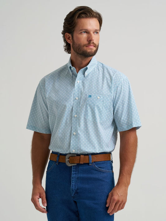 Man wearing a light blue patterned  Wrangler shirt and dark blue jeans on a plain background