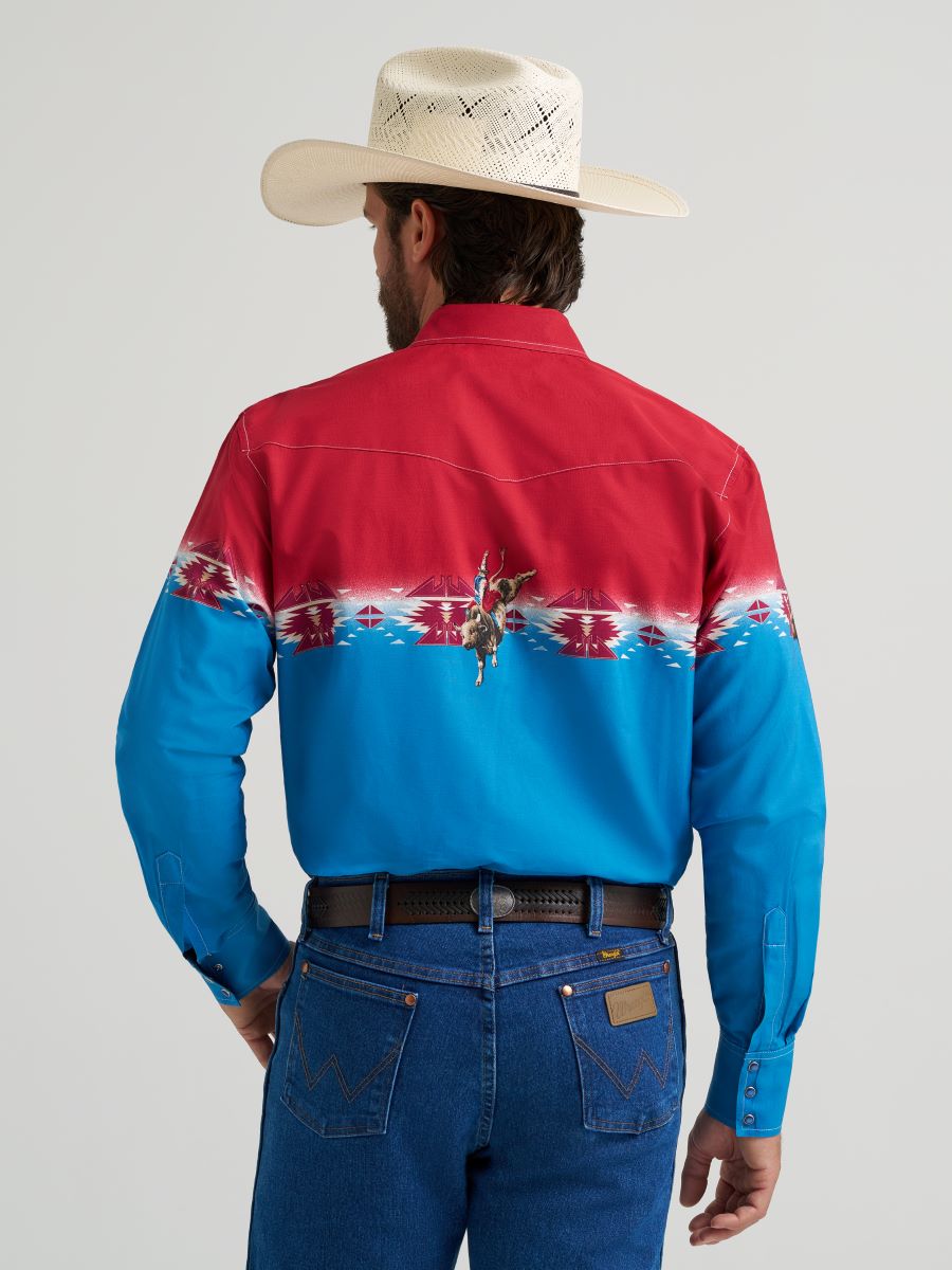 Man wearing a red and blue patterned Wrangler shirt with a cowboy hat on a gray background