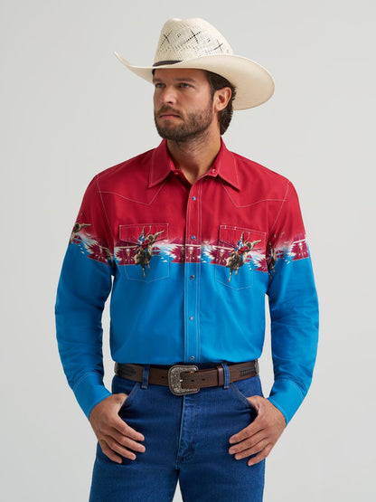 Man wearing a red and blue Wrangler western-style shirt with cowboy hat on a gray background
