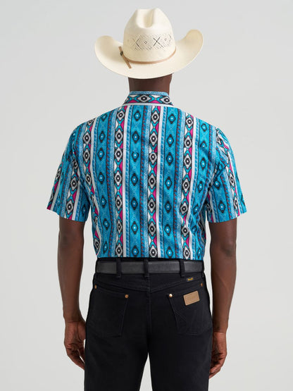 man wearing a Blue Wrangler shirt with hat and blue jeans on a grey background
