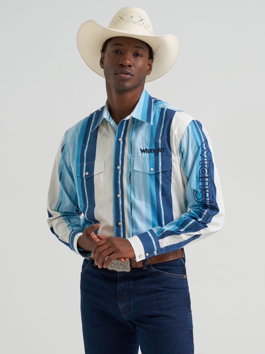Man wearing a blue striped Wrangler shirt with a logo, dark jeans, and a cowboy hat on a light gray background