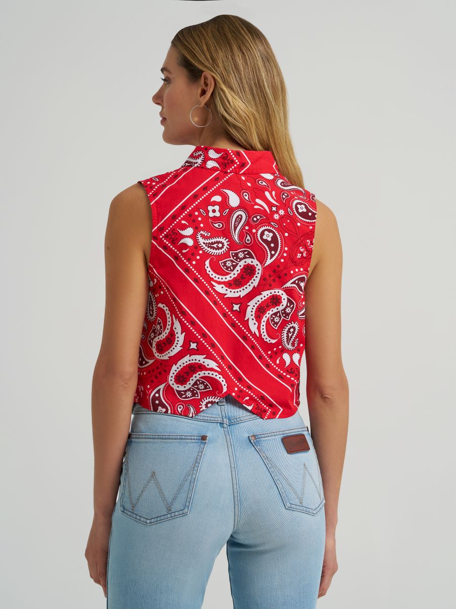 Woman wearing a red Wrangler paisley tank top and blue jeans on a grey background