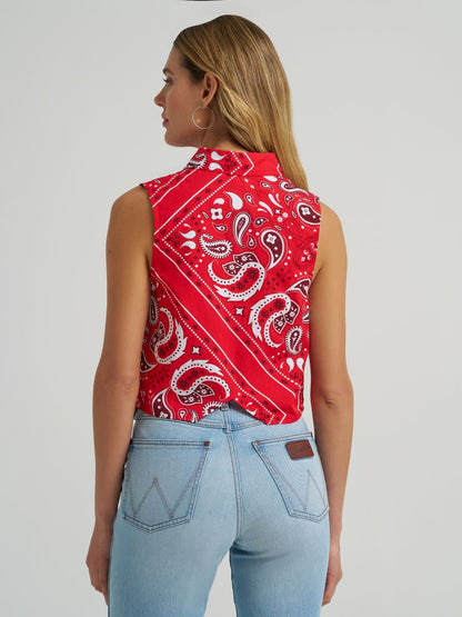 Woman wearing a red Wrangler paisley tank top and blue jeans on a grey background
