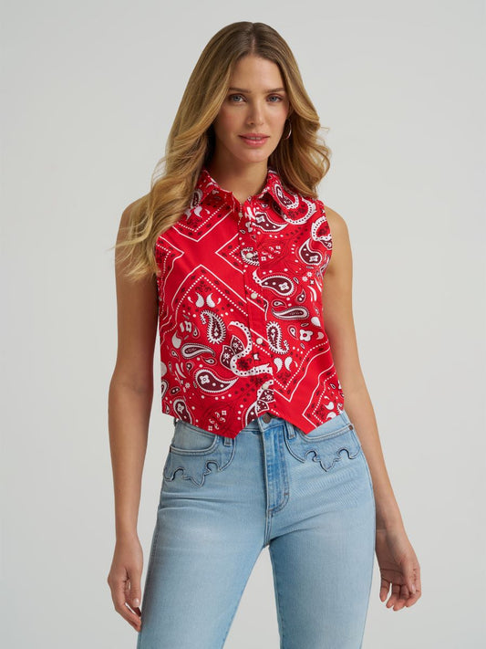 Woman wearing a red Wrangler paisley tank top and blue jeans on a grey background