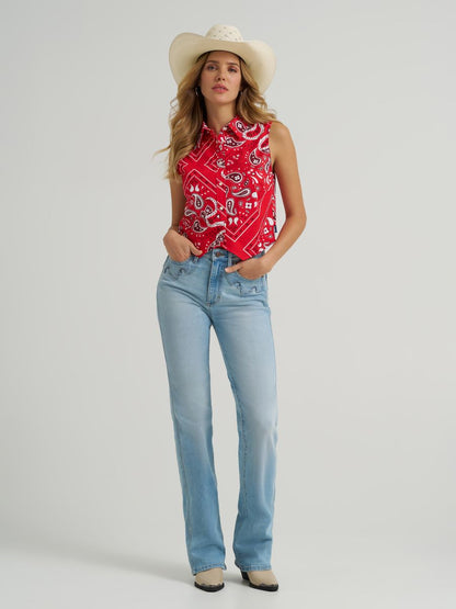 Woman wearing a red Wrangler paisley tank top cowboy hat and blue jeans on a grey background