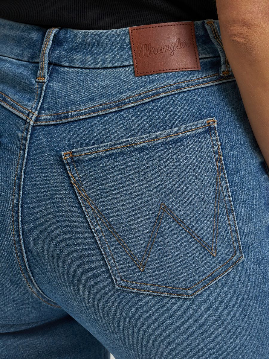 Close-up of blue jeans with a wrangler brand label on the back pocket.