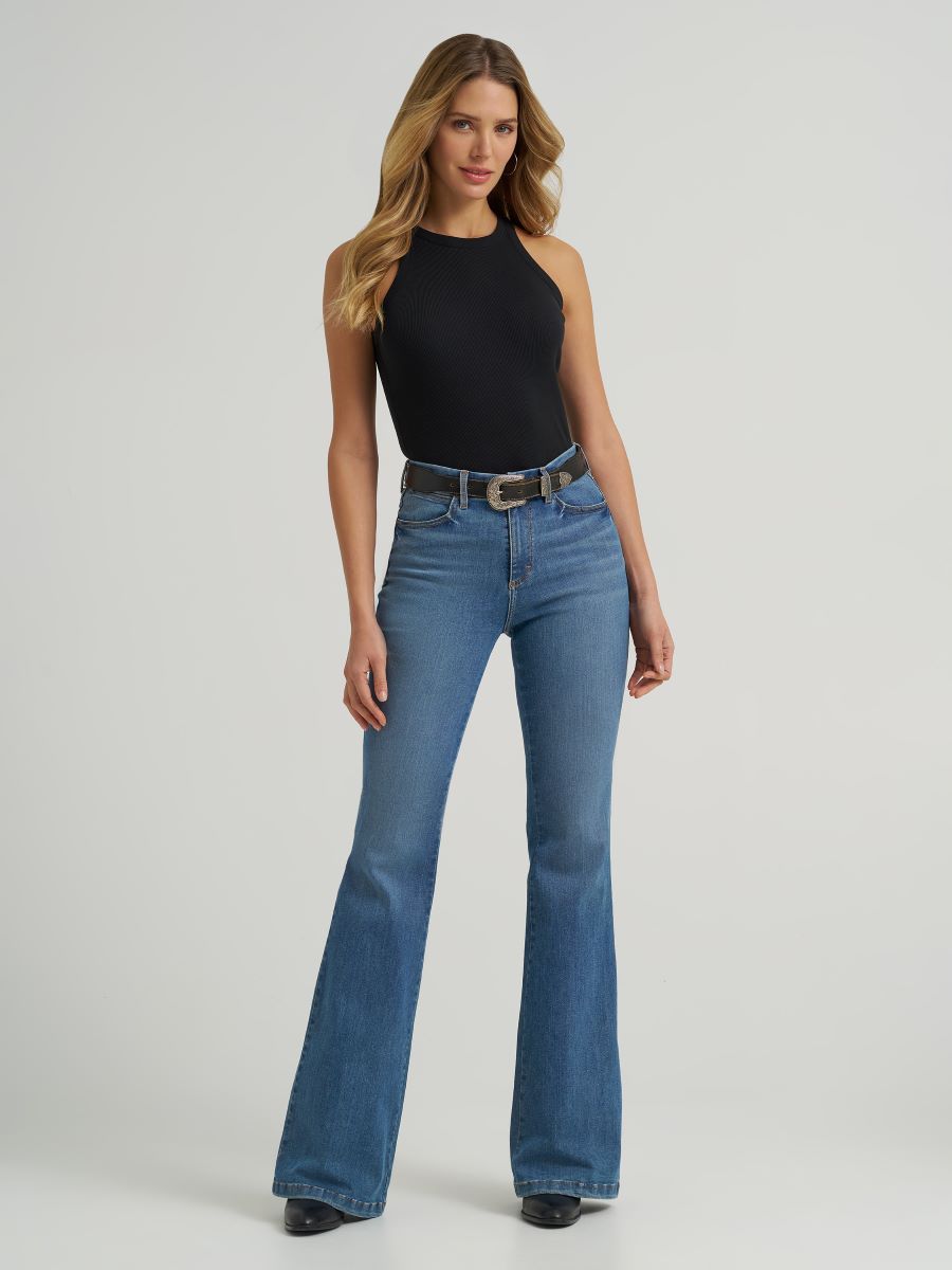 woman wearing blue flare jeans and a black tank top on a white background