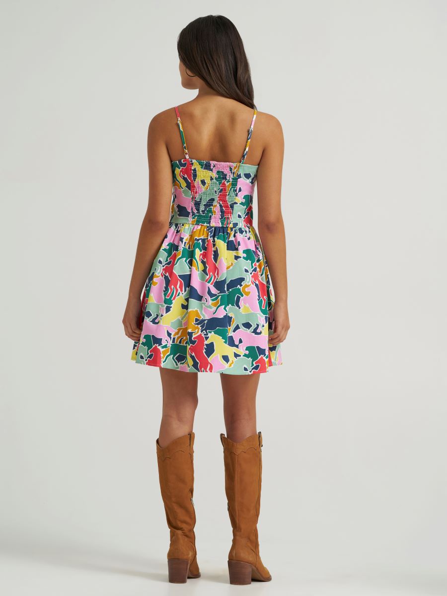 Woman wearing a colorful Wrangler dress with brown knee-high boots on a white background