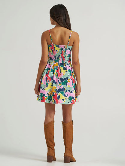 Woman wearing a colorful Wrangler dress with brown knee-high boots on a white background