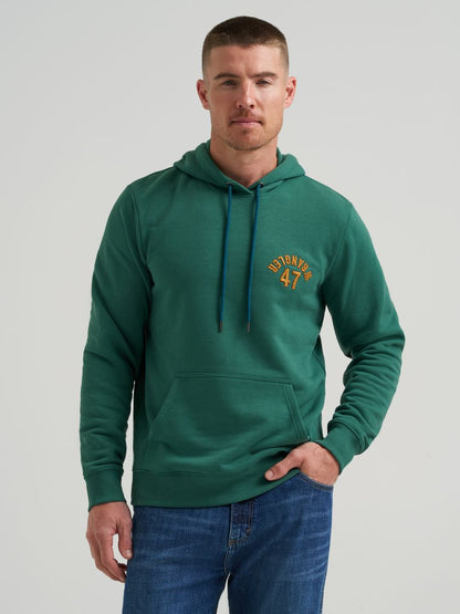 Man wearing a green Wrangler hoodie with text on a plain background