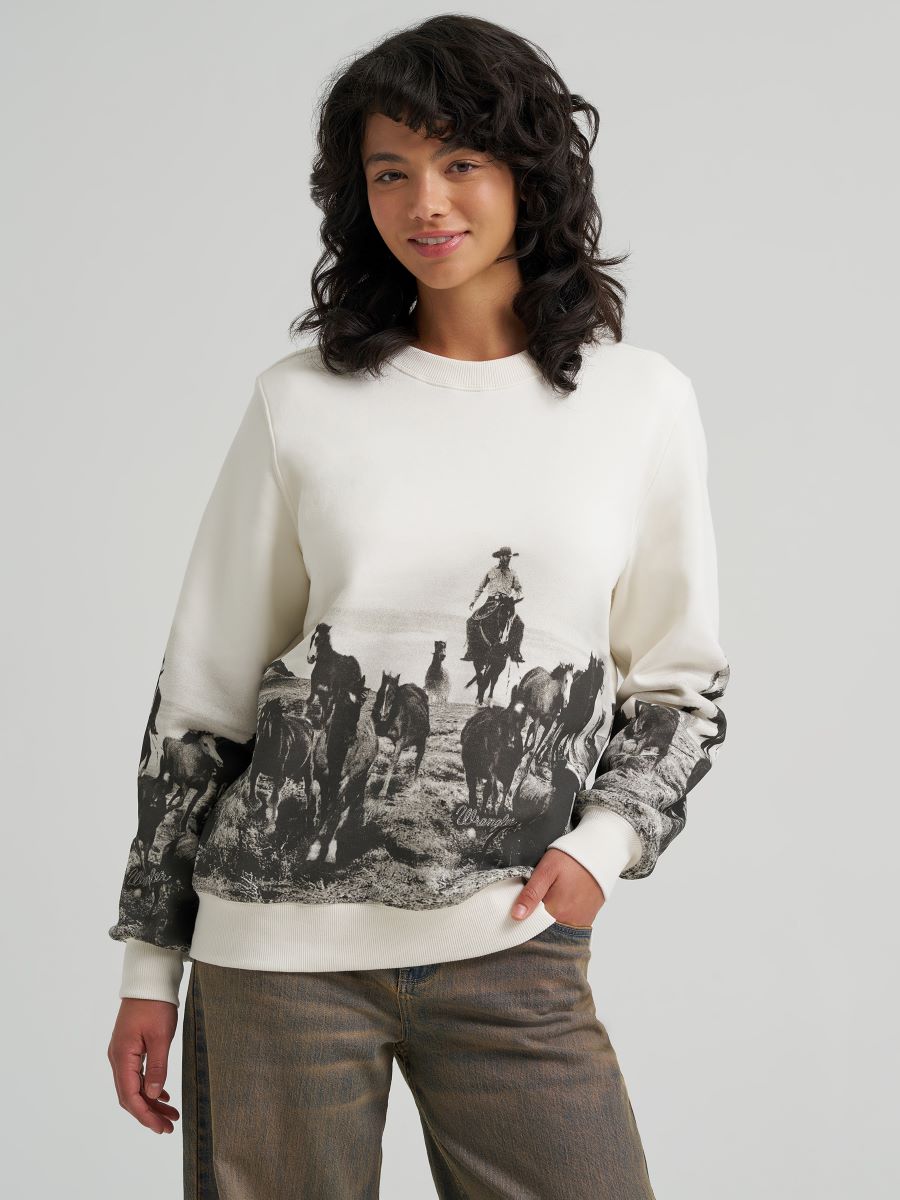 Person wearing a white Wrangler sweater with a graphic of cowboys on horses