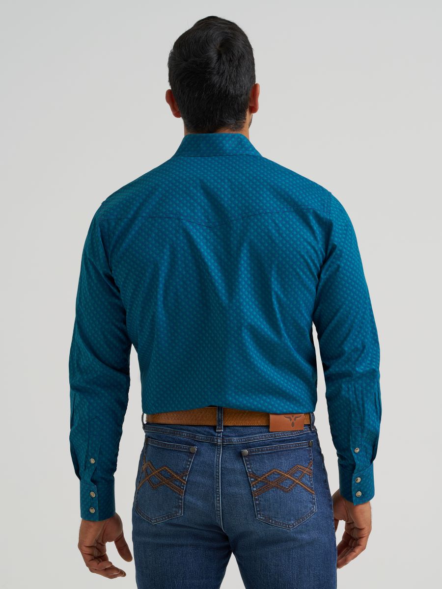 Man wearing a blue patterned Wrangler shirt and jeans on a gray background