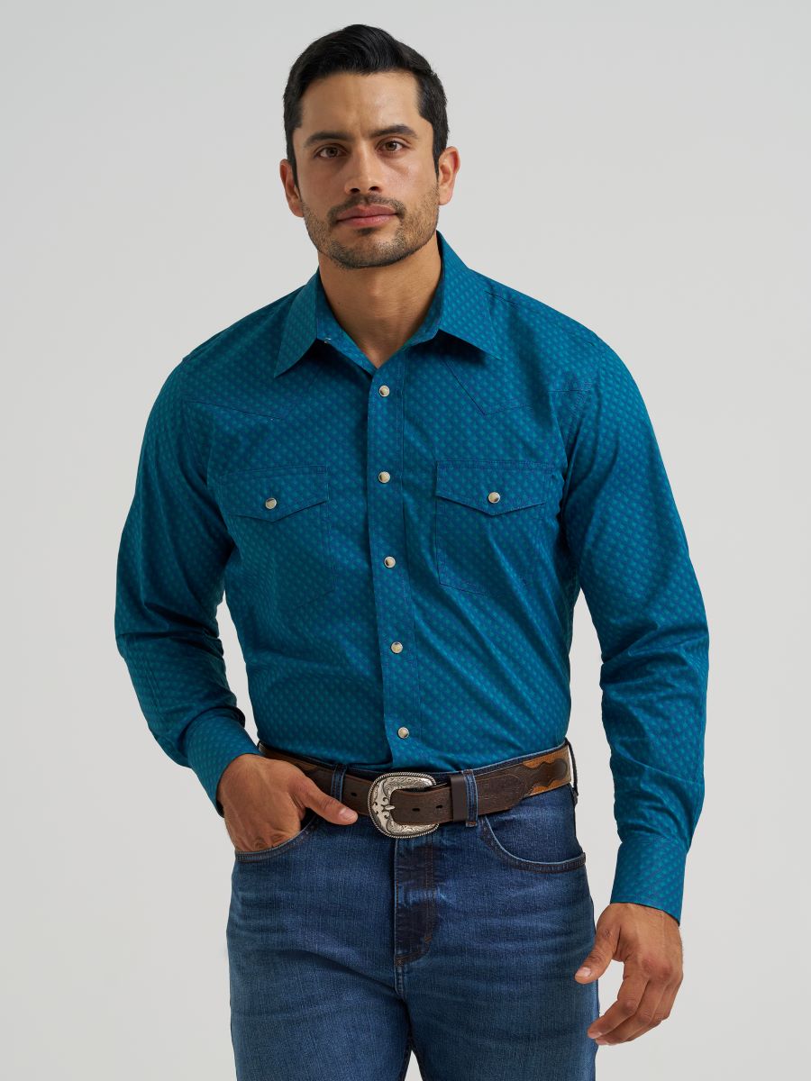 Man wearing a blue Wrangler patterned shirt and jeans on a gray background