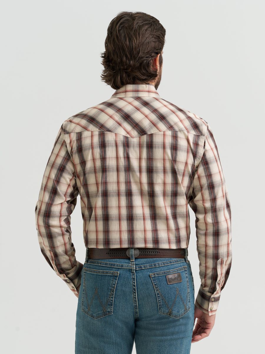 Man wearing a brown plaid Wrangler shirt and jeans on a light gray background