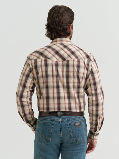 Man wearing a brown plaid Wrangler shirt and jeans on a light gray background