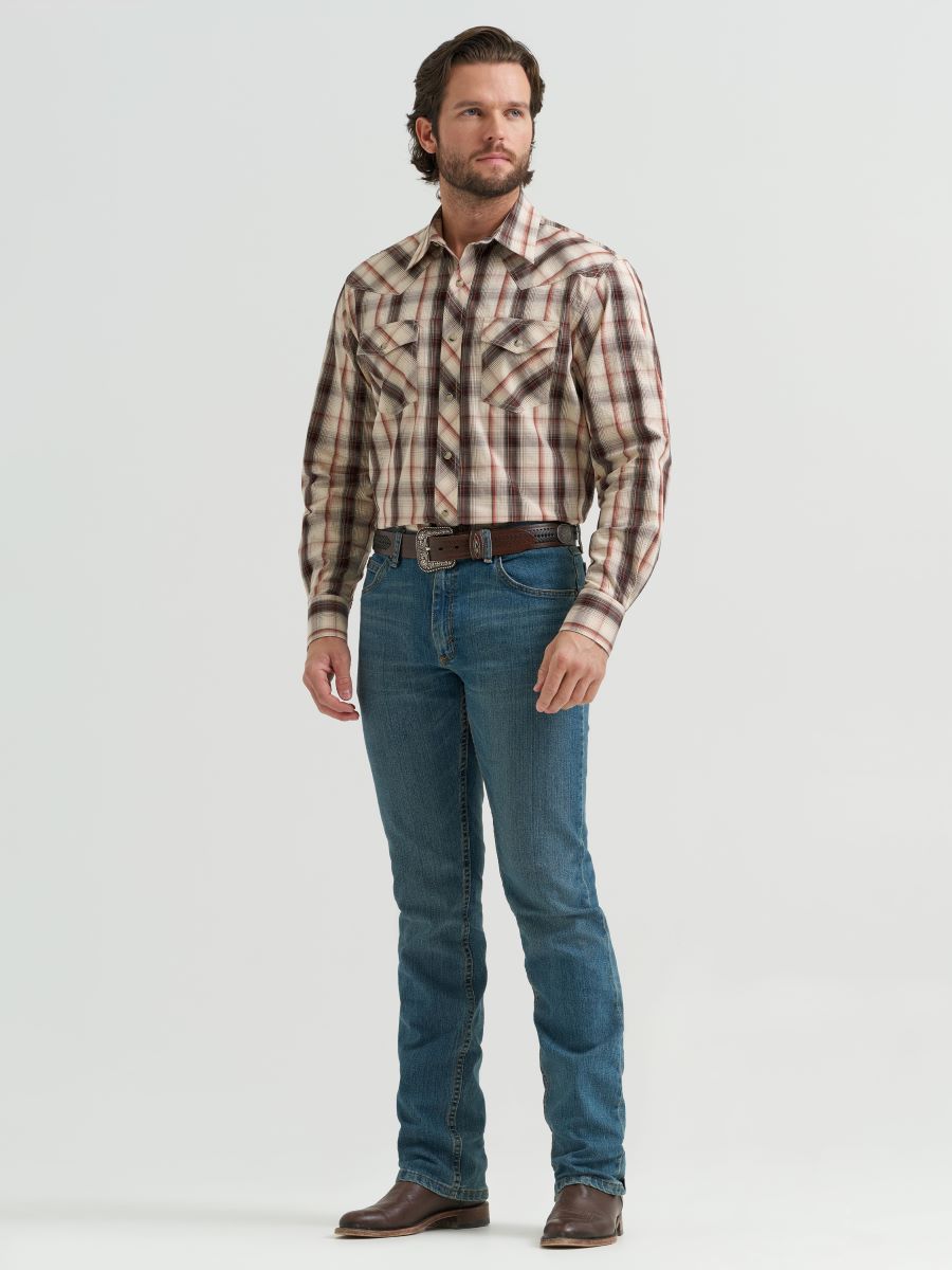 Man wearing a brown plaid Wrangler shirt and blue jeans on a white background